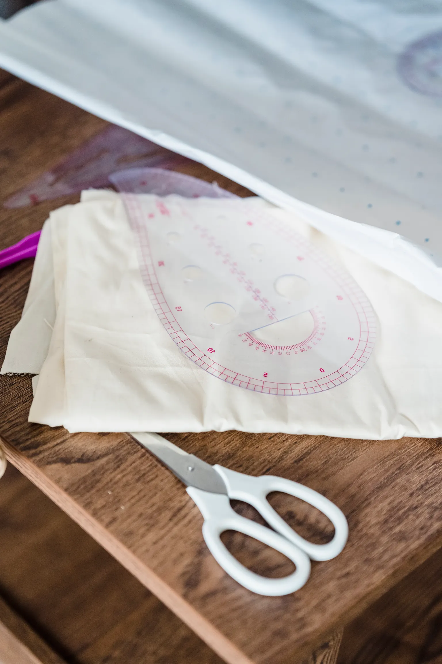 Fabric scissors resting beside sewing patterns and material on a worktable